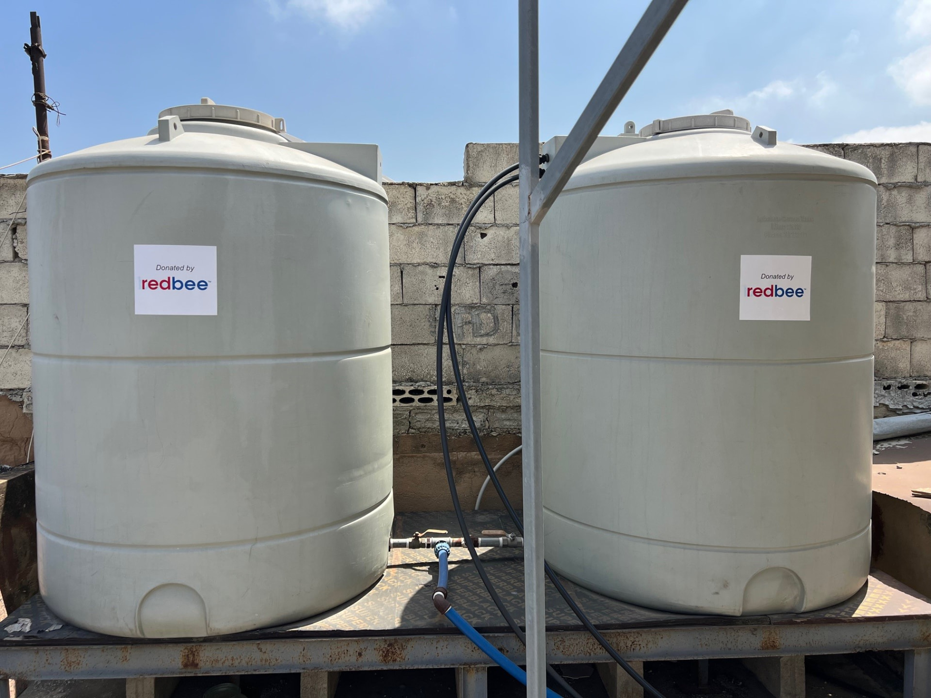 Two water storage tanks labelled Donated by RedBee on a rooftop